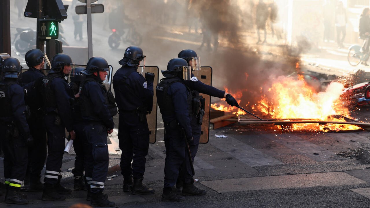 French riot police stand beside a burning fire in Paris